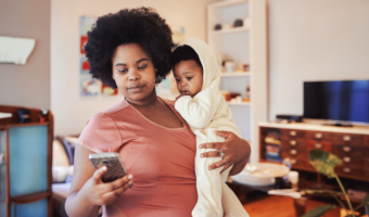 Mom on her phone while carrying her baby.