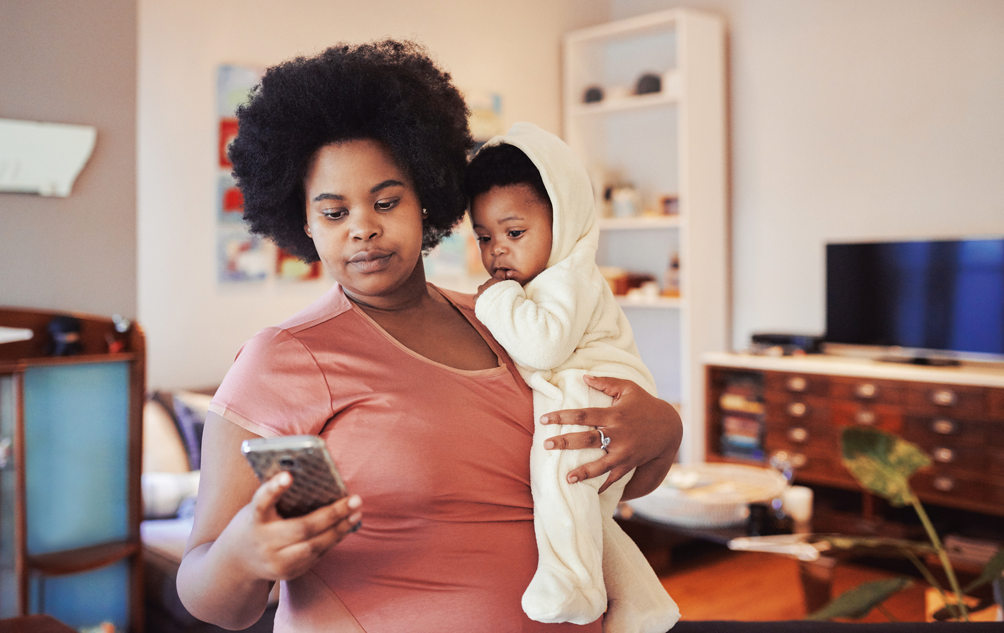 Mom on her phone while carrying her baby.